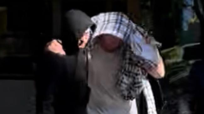 Nathan Bernhard leaving Nowra Police Station, hidden under blanket. Picture: Tom McGann