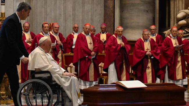 Pope Francis is pushed on a wheelchair by the coffin of Australia's Cardinal George Pell, during a funeral mass in the St. Peter’s basilica at the Vatican. Picture: AFP