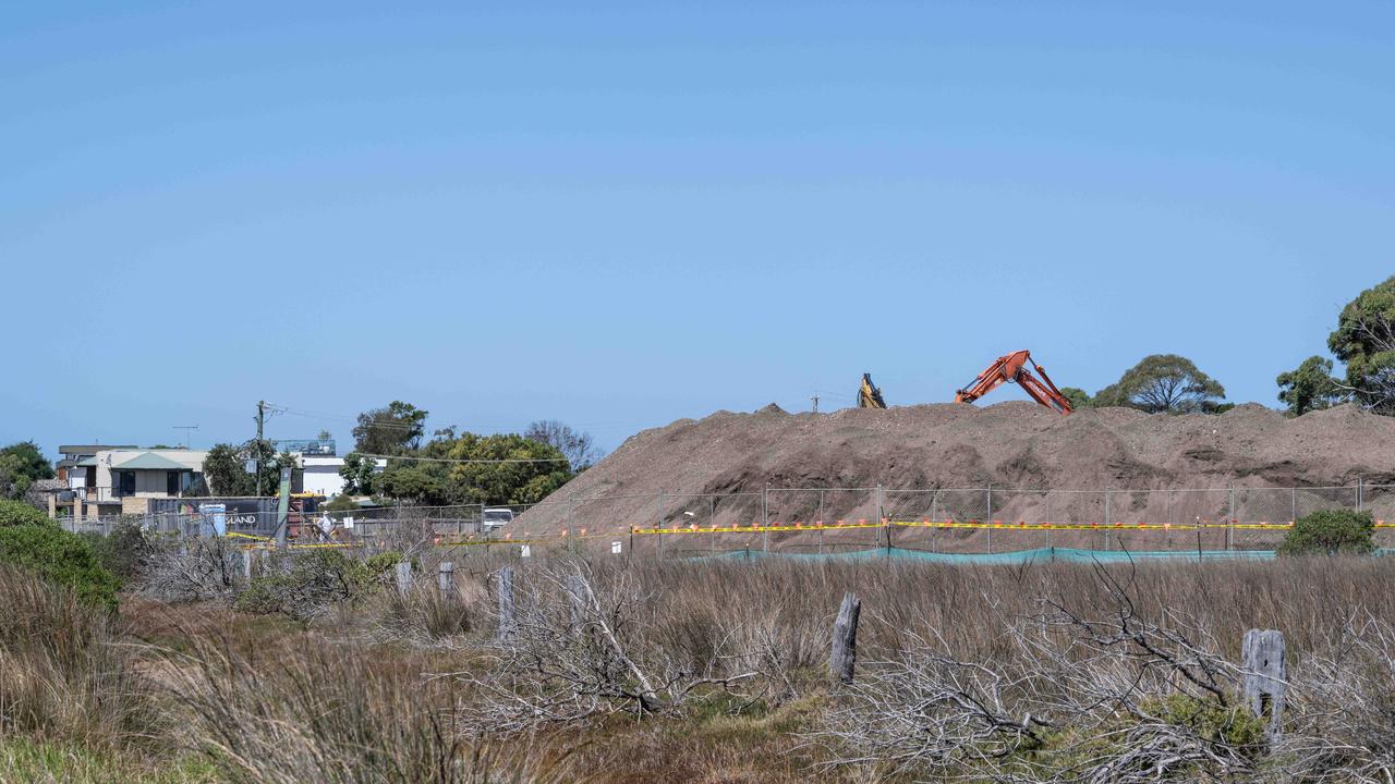 In March, workers in protective equipment move contaminated soil with asbestos signs around the building site in Murray Road, Queenscliff. Picture: Brad Fleet