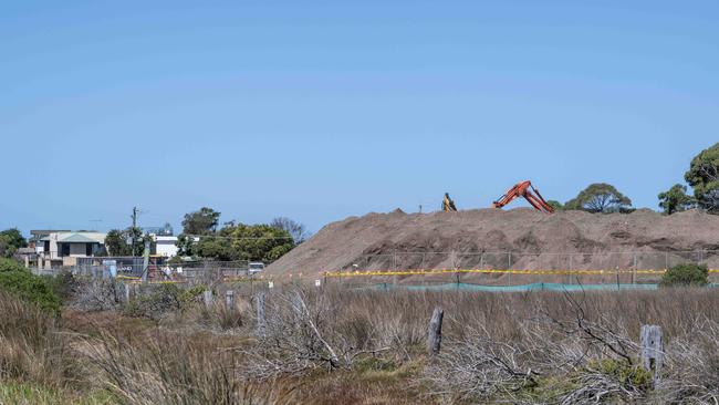 In March, workers in protective equipment move contaminated soil with asbestos signs around the building site in Murray Road, Queenscliff. Picture: Brad Fleet