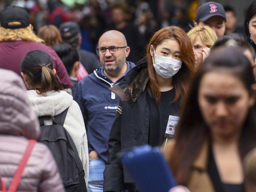 A woman wearing a face mask crosses the street in Melbourne. Wearing masks is still a rarity in Australia, as opposed to many Asian nations where it is much more prevalent. Picture: William WEST / AFP.