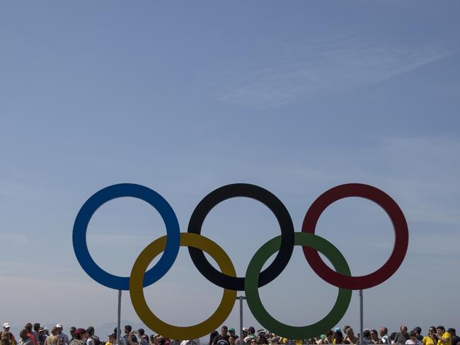 Spectators stand behind the Olympic rings after men's marathon event at the 2016 Summer Olympics in Rio de Janeiro, Brazil, Tuesday, Aug. 16, 2016. (AP Photo/Felipe Dana)