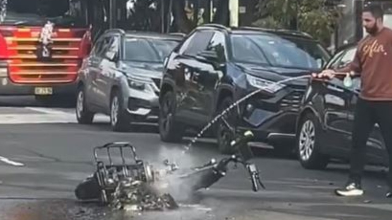 A man hoses the burnt e-bike after the fire. Picture: Supplied