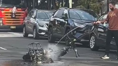 A man hoses the burnt e-bike after the fire. Picture: Supplied