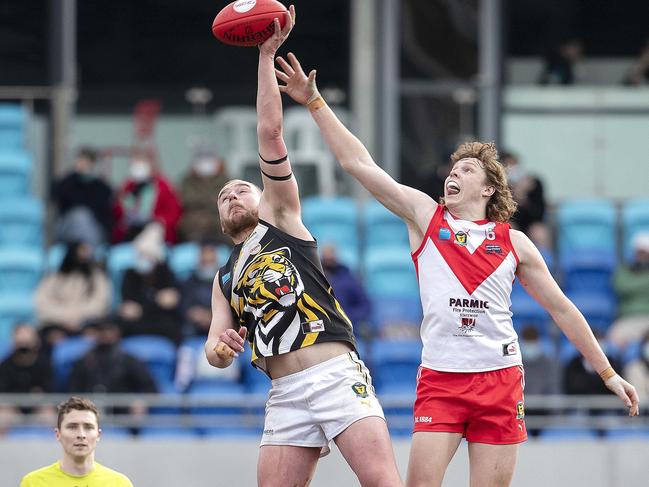 Tigers’ Marcus Gardner out-stretches Clarence’s Sam Green to hit the ball first. Picture: Chris Kidd