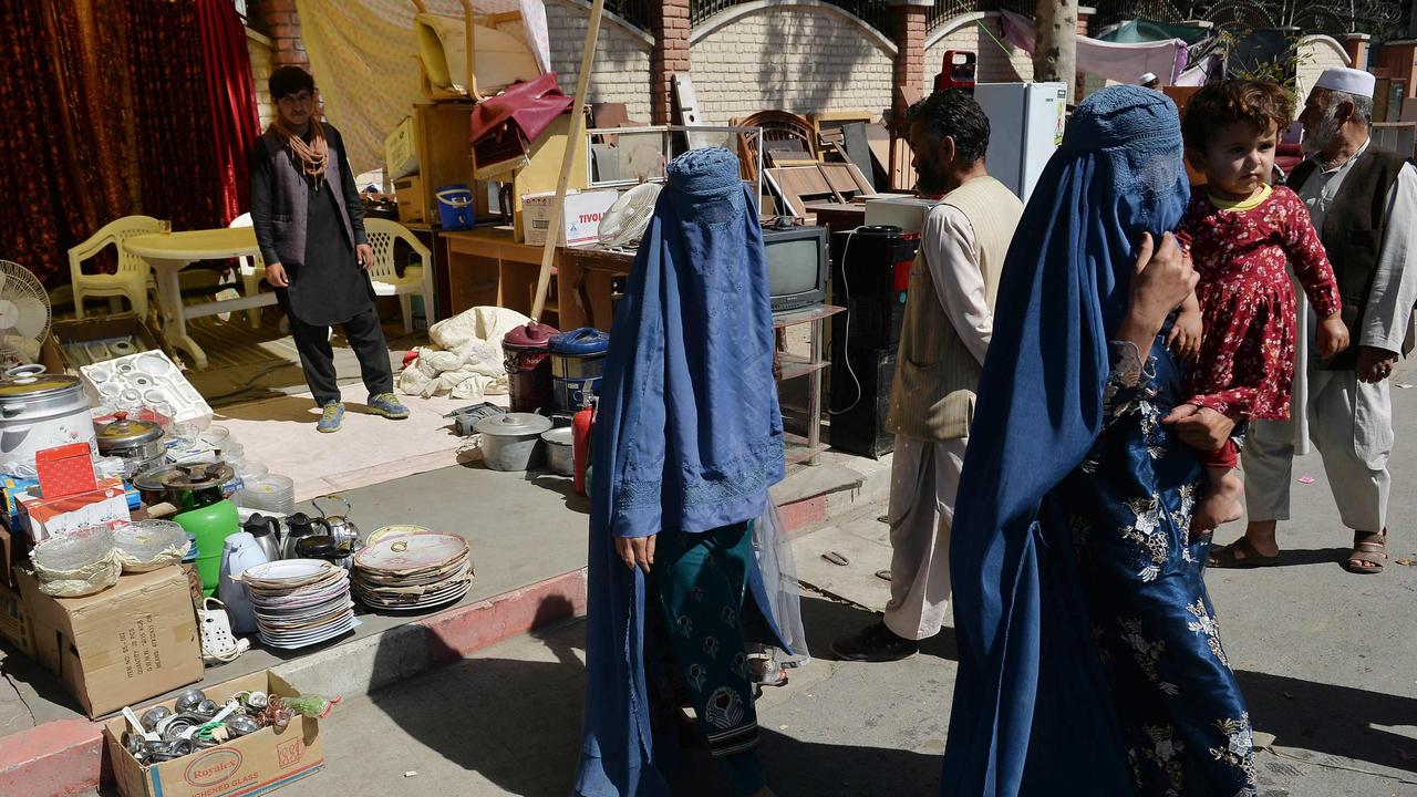 Burqa-clad women carrying a child walk along a temporary second-hand market in Kabul’s Chaman-e-Huzuri neighbourhood on September 16, 2021. Picture: Hoshang Hashimi/AFP