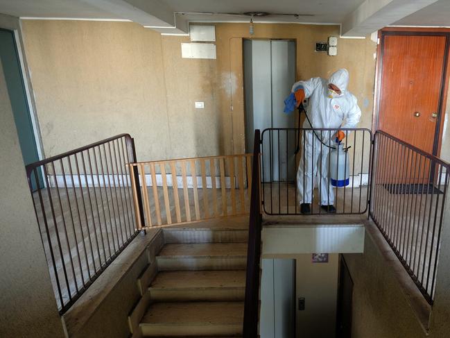 A man wearing a protective suit sanitises the stairway of a public housing building in Rome. Picture: AP