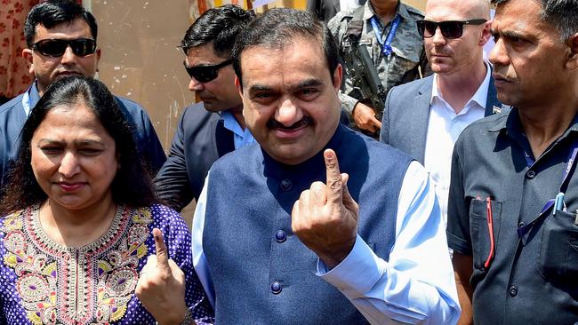 Gautam Adani and his wife Priti Adani (2L) show their inked finger after casting their ballot to vote in India's general election. Picture: AFP.