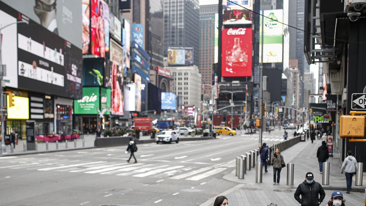 Pedestrians wear protective masks while walking through a sparsely populated Times Square due to COVID-19 concerns, Friday, March 20, 2020, in New York. Picture: AP /John Minchillo.