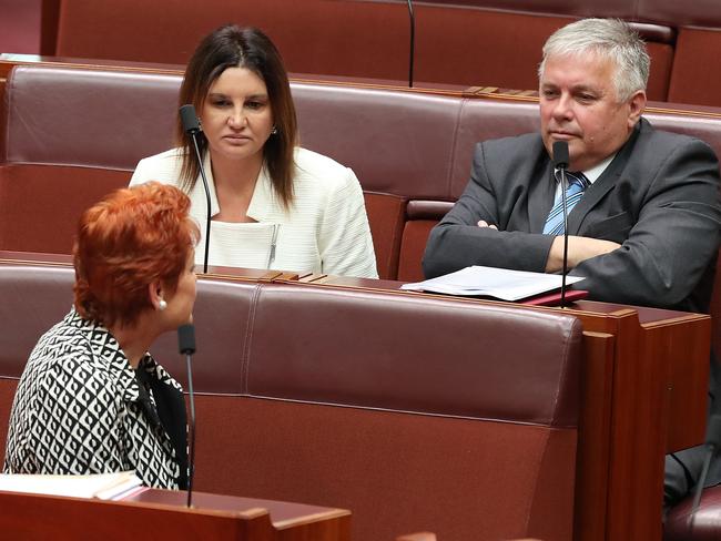 Senator Jacqui Lambie and Senator Rex Patrick speaking to Senator Pauline Hanson in the senate Chamber at Parliament House in Canberra.