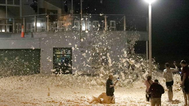 Locals get amongst the sea foam in front of The beach Club at Collaroy on Sunday night. Picture: Damian Shaw