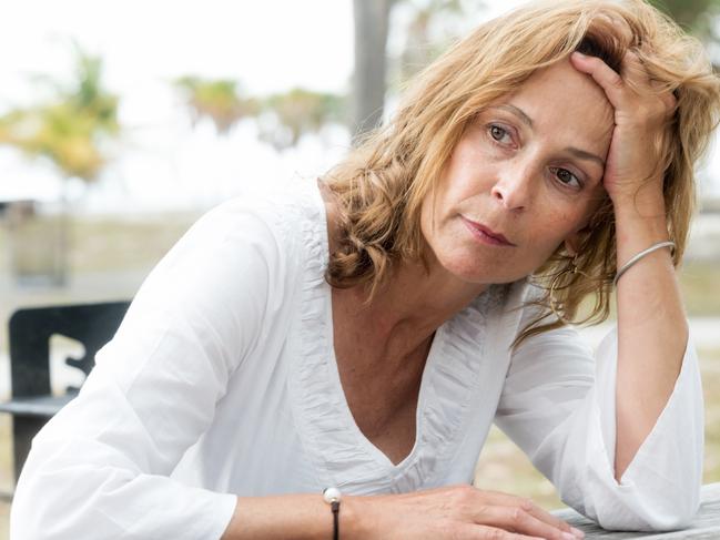 A woman looking stressed sitting outside at a table. Picture: iStock.