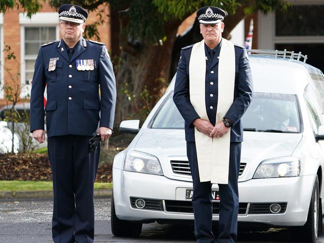 Victoria Police Chief Commissioner Graham Ashton and Senior Police Chaplain Jim Jung look on as the hearse leaves the funeral of Leading Senior Constable Lynette Taylor at the Victoria Police Academy in Melbourne, Thursday, April 30, 2020. Leading Senior Constable Lynette Taylor, Senior Constable Kevin King and constables Glen Humphris and Josh Prestney were killed in the line of duty last week when a truck crashed into them on the Eastern Freeway at Kew. (AAP Image/Scott Barbour) NO ARCHIVING