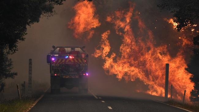 A fire truck drives through the Nana Glen fire on November 12 last year. Picture: AAP Image/Dan Peled