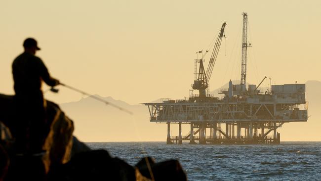 A person fishes with offshore oil and gas platform Esther in the distance in Seal Beach, California. Photo: Mario Tama/Getty Images/AFP