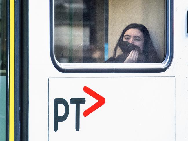 A woman covers her face on a Swanston Street tram. Picture: Tony Gough