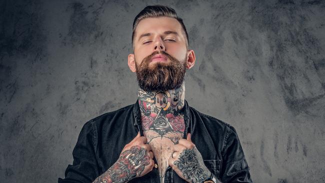 Studio portrait of bearded hipster man with tattoos on his arms, chest and neck; tattoo generic