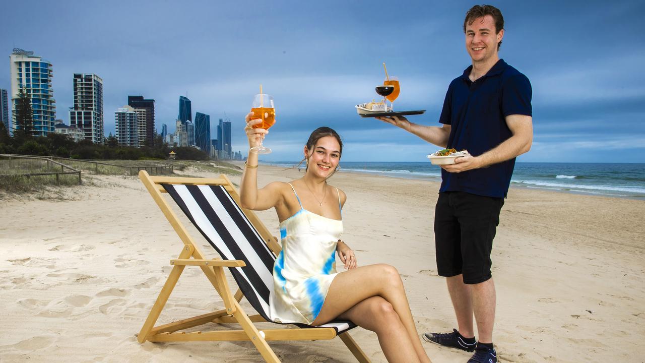 Bartender Tallis Muddle and Hannah Bemrose toast the Gold Coast’s first beach bar trial. Beach bars have been identified as an emerging opportunity for the tourism industry. Picture: Nigel Hallett