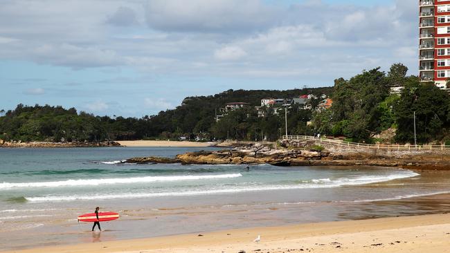 A lone surfer walks up Manly beach on March 23. Picture: Cameron Spence/Getty Images