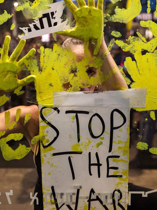 A woman stamps her painted hands behind a sign as Israeli anti-government demonstrators protest calling for action to secure the release of hostages held captive since the October 7 attacks.