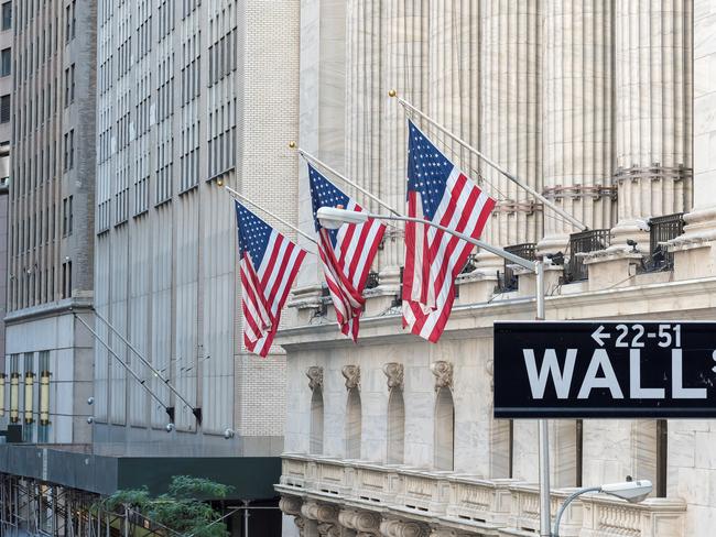 Wall Street sign with american flags and New York Stock Exchange in Manhattan, New York City, USA.