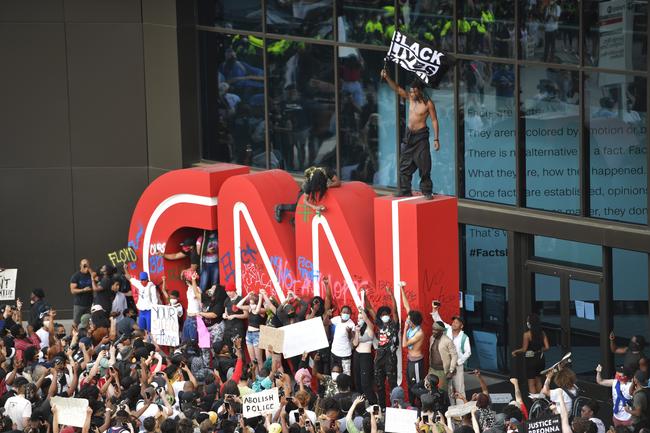 Demonstrators graffiti the CNN logo in Atlanta. Picture: AP