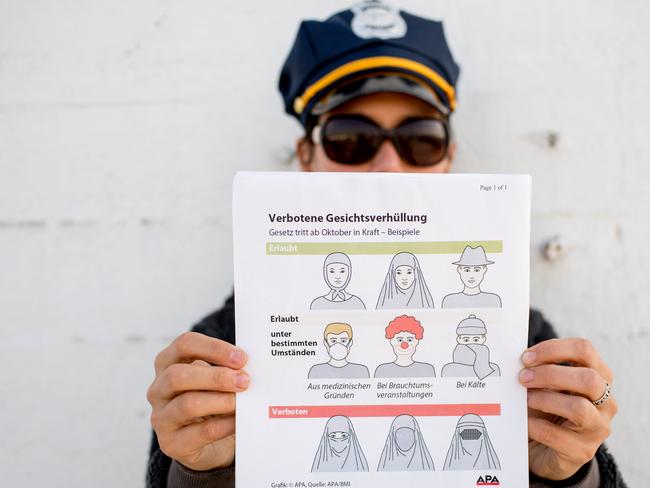 This illustration photo shows a model holding up an information pamphlet about new Austrian restrictions banning the wearing of burqas and other items covering the face in public places. Picture: AFP.