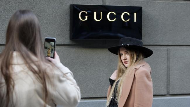 KIEV, UKRAINE - 2021/03/06: A young woman poses for a photo in front of Gucci logo, of a luxury fashion house, outside a Gucci brand store. (Photo by Pavlo Gonchar/SOPA Images/LightRocket via Getty Images)