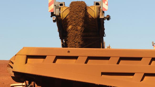 An earth mover receives iron ore from a surface miner in the mine pit at Fortescue Metals Group Ltd.'s Cloudbreak operation in the Pilbara region of Western Australia, on Monday, July 25, 2011. Fortescue Metals Group, Australia's third-biggest producer of iron ore, will release their full-year earnings on August 19. Photographer: Carla Gottgens/Bloomberg