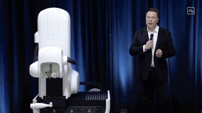 This video grab from the Neuralink livestream shows Elon Musk standing next to the surgical robot used to implant the chips into pings’ brains. Picture: Neuralink / AFP