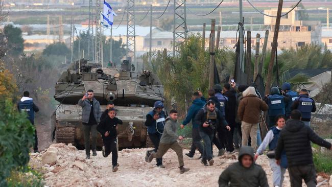 Palestinian children and journalists run as Israeli tanks enter the Jenin camp for Palestinian refugees in the occupied West Bank.