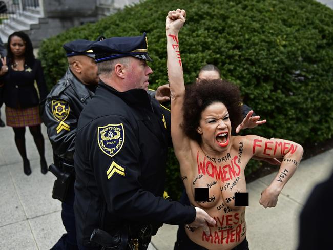 A protester is detained as Bill Cosby arrives for his sexual assault trial at the Montgomery County Courthouse on the outskirts of Philadelphia. Picture: AP Photo/Corey Perrine