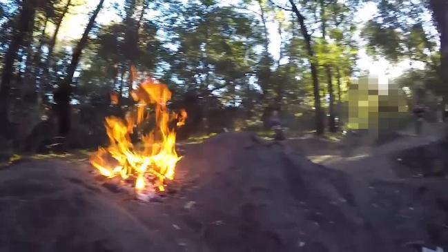 Kids on bikes jump over a fire pit