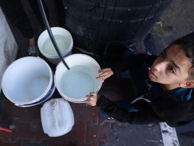 A Palestinian youth fills a bucket with water at the Rafah refugee camp in the southern Gaza Strip. Israel has claimed that it is restarting the water supply to parts of the Gaza Strip amid concern of mass dehydration. Picture: Mohammed Abed/AFP