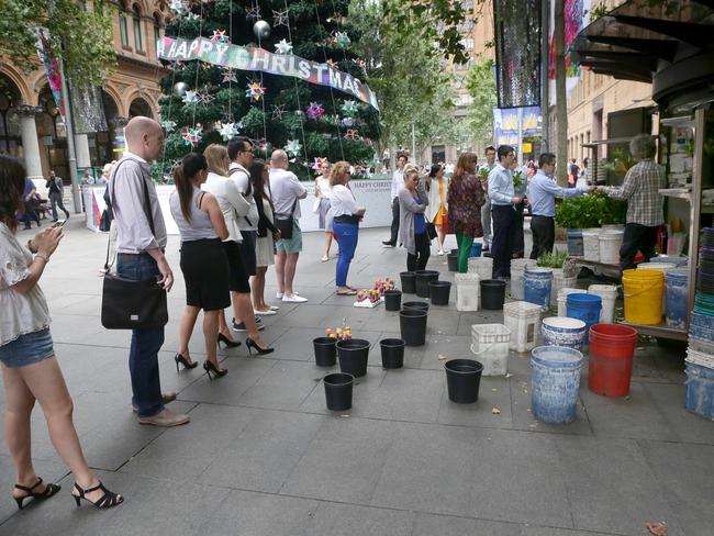 City workers line up to buy flowers from florist George Lackerdis as empty buckets pay mute tribute to the depth of Sydneysiders’ mourning. Picture: Adam Ward