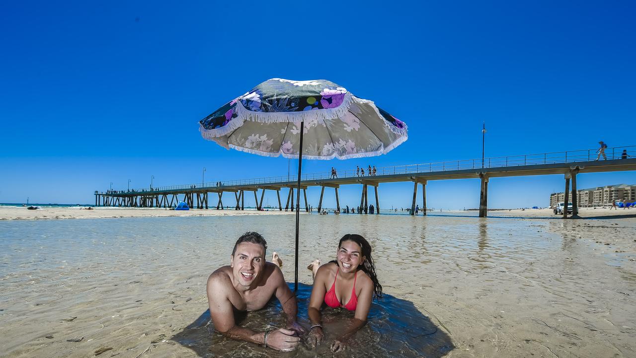 Renato Lovisa of Italy and Natasha Romano of Newton find the best way to cool off in a tidal pool under a beach umbrella at Glenelg. Picture. ROY VANDERVEGT