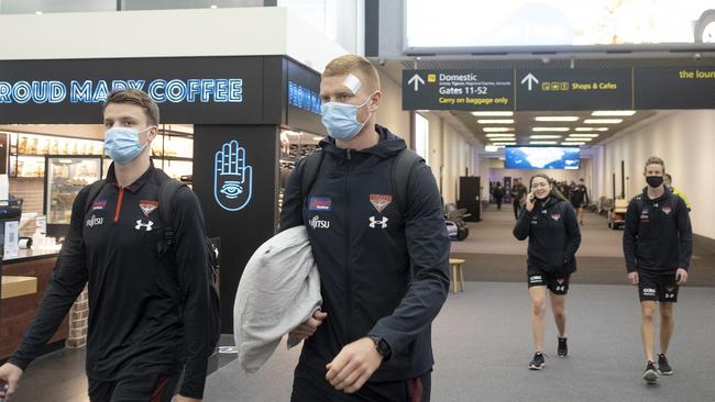 MPs aren’t the only ones urged to not risk border closures: Essendon AFL players are seen walking to board a plane for Perth, at Tullamarine airport on Wednesday. Picture: NCA NewsWire / Luis Enrique Ascui