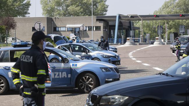 Police officers stop cars at the Melegnano highway barrier entrance, near Milan, Italy, Saturday, April 11, 2020. Using helicopters, drones and stepped-up police checks to make sure Italians don't slip out of their homes for the Easter holiday weekend, Italian authorities are doubling down on their crackdown against violators of the nationwide lockdown decree. The new coronavirus causes mild or moderate symptoms for most people, but for some, especially older adults and people with existing health problems, it can cause more severe illness or death. (AP Photo/Luca Bruno)