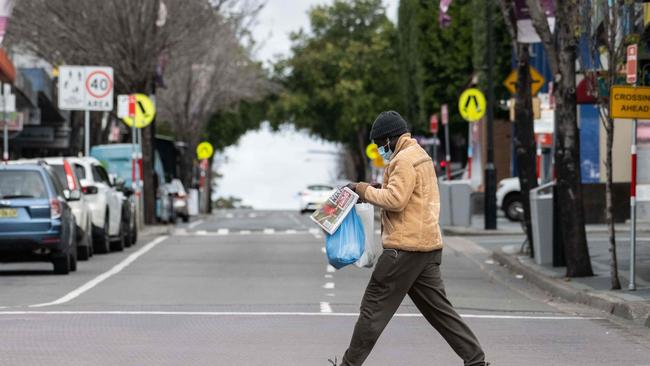 A lone man crosses a quiet road whilst wearing a mask in Blacktown, Sydney. Picture: NCA NewsWire / James Gourley