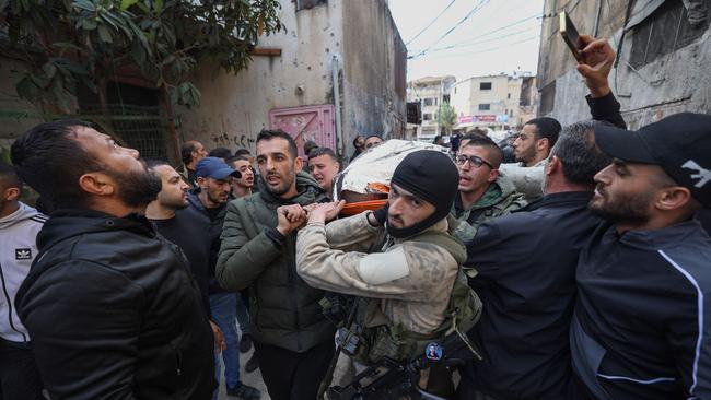 Palestinian gunmen and residents evacuate the body of a man killed in an earlier Israeli raid at the Nur Shams refugee camp near Tulkarm on March 21, amid a surge of violence in the Israel-occupied West Bank while battles continue between Israel and Hamas militants in the Gaza Strip.