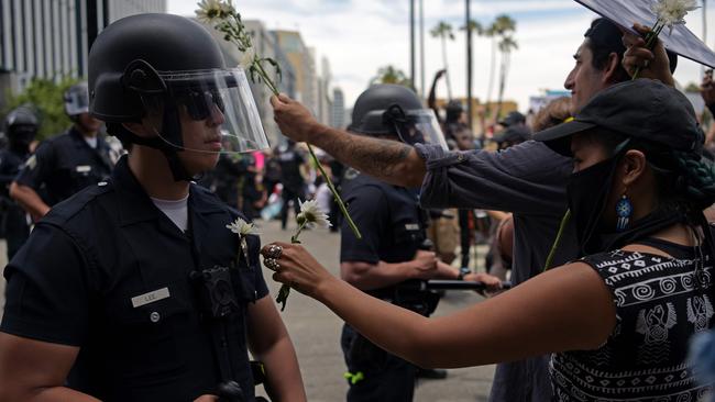 A protester puts a flower in the pocket of an LAPD officer during a demonstration over the death of George Floyd in Hollywood, California on June 2, 2020. The LAPD will trial XReality’s VR tech for three months. Picture: Agustin Paullier / AFP)