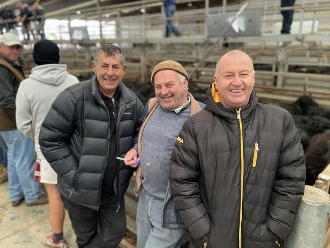 Friends Terry Tairovski, left, and Peno Huseni, right, bought 35 Angus heifer calves for $1210 at the Pakenham store sale. They are pictured with their agent Wayne Barker, center.