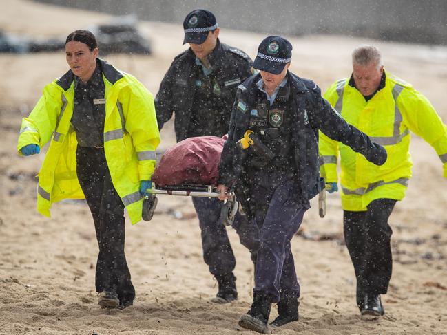 Police and contractors remove the body from the beach.