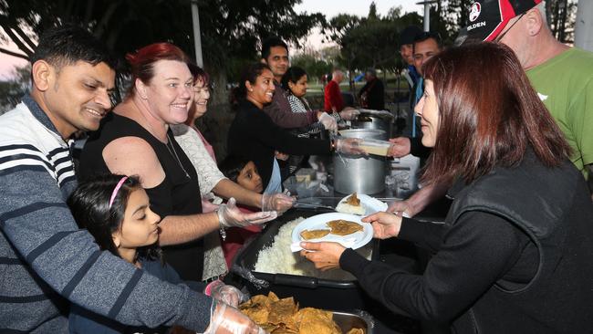 Shirlian Noy (red hair left side) volunteers for her charity Helping Hands, serving the homeless a special Indian feast at Lenfox Park Labrador. Picture Glenn Hampson