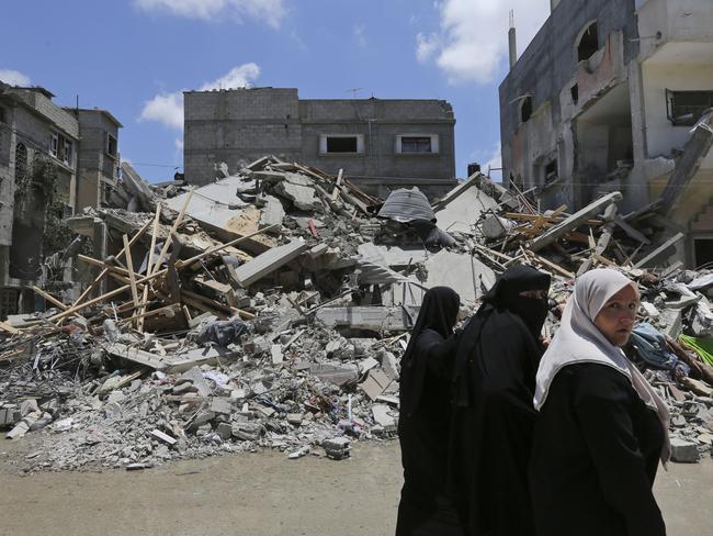 Palestinians walk by the rubble of a house destroyed by an overnight Israeli missile strike. AP Photo/Lefteris Pitarakis