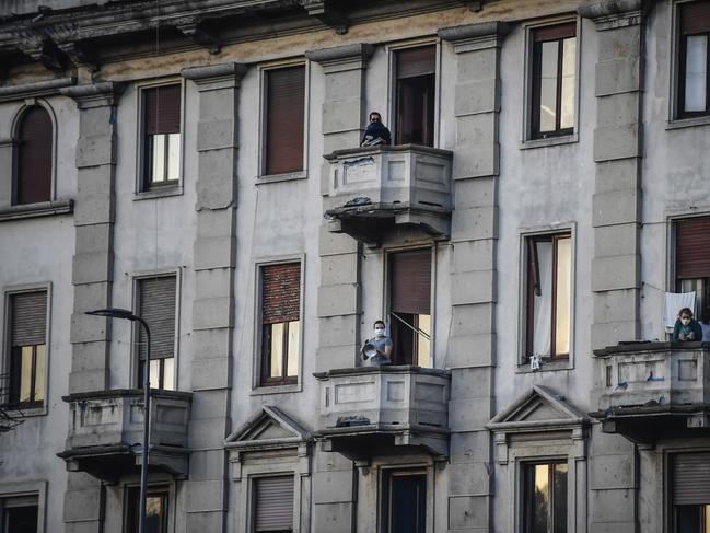 People lean out of their balconies in Milan to play and sing during a flash mob launched throughout Italy to bring people together and try to cope with the emergency of coronavirus. Picture: AP