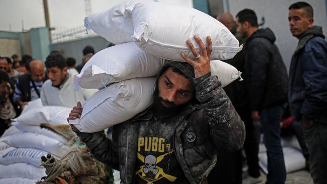 A Palestinian man carries sacks of humanitarian aid at the UNRWA distribution centre in Rafah, Palestine. Picture: AFP