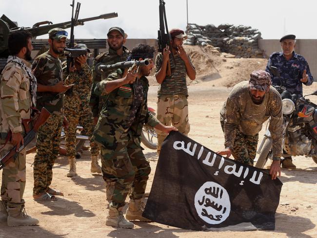 Terror group grows ... Iraqi security forces hold a flag of the Islamic State group they captured during an operation outside Amirli, north of Baghdad, Iraq. Picture: AP