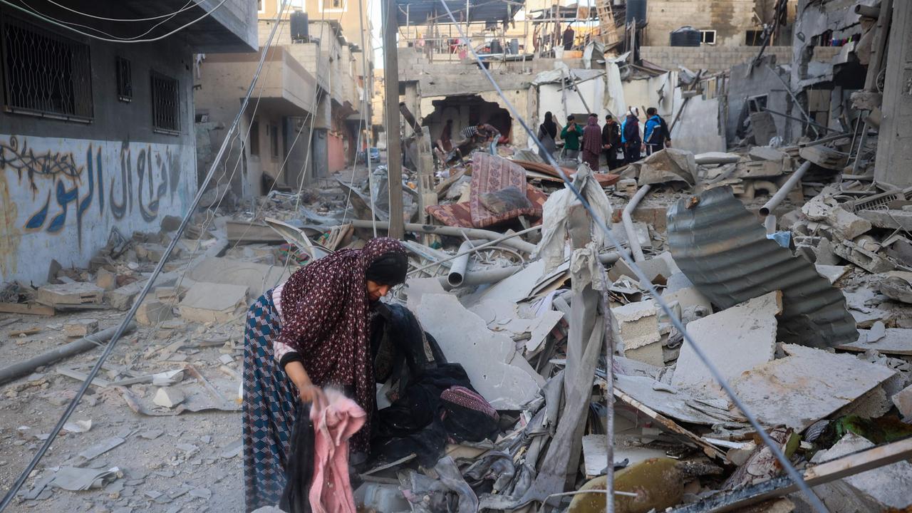 A woman searches through the rubble of her home, destroyed in an Israeli strike, for salvageable items at the Nuseirat refugee camp in the central Gaza Strip on March 18, 2025. (Photo by Eyad BABA / AFP)