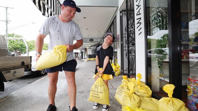 Alister Reid and son Oliver of Ashgrove in Brisbane carry sandbags to help with flood defence. Picture: Annette Dew